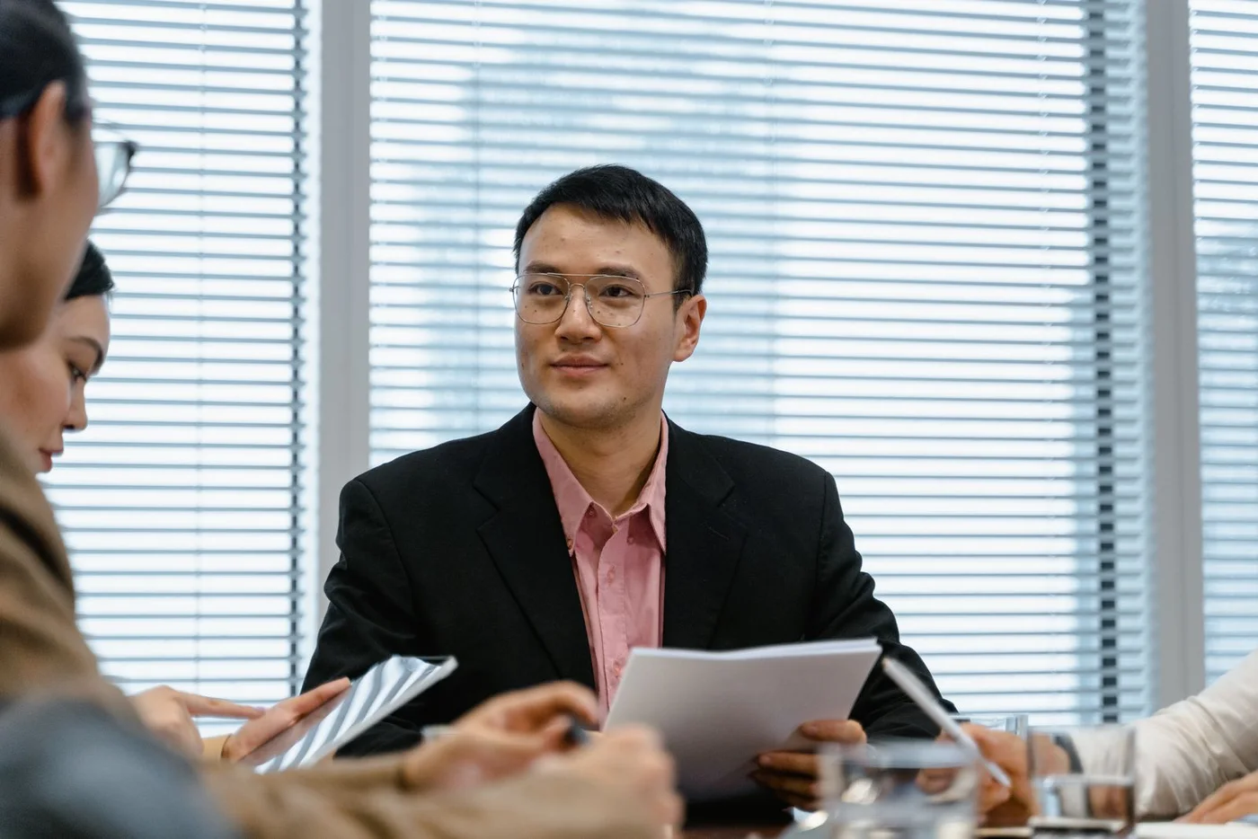 A man discussing a project with colleagues around a meeting table.