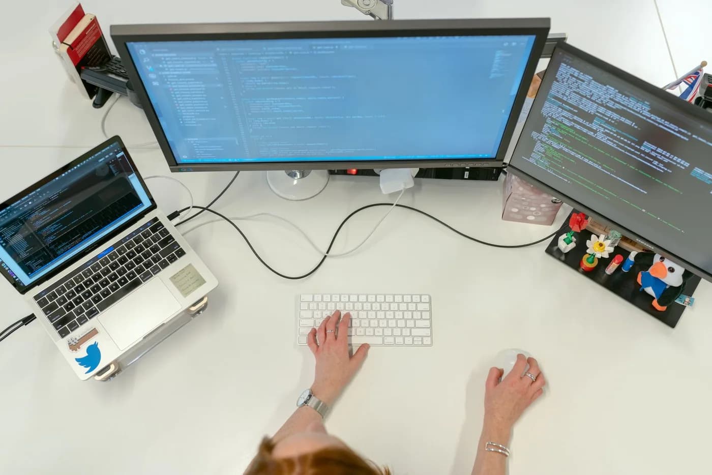 A software engineer working with two monitors and a laptop.