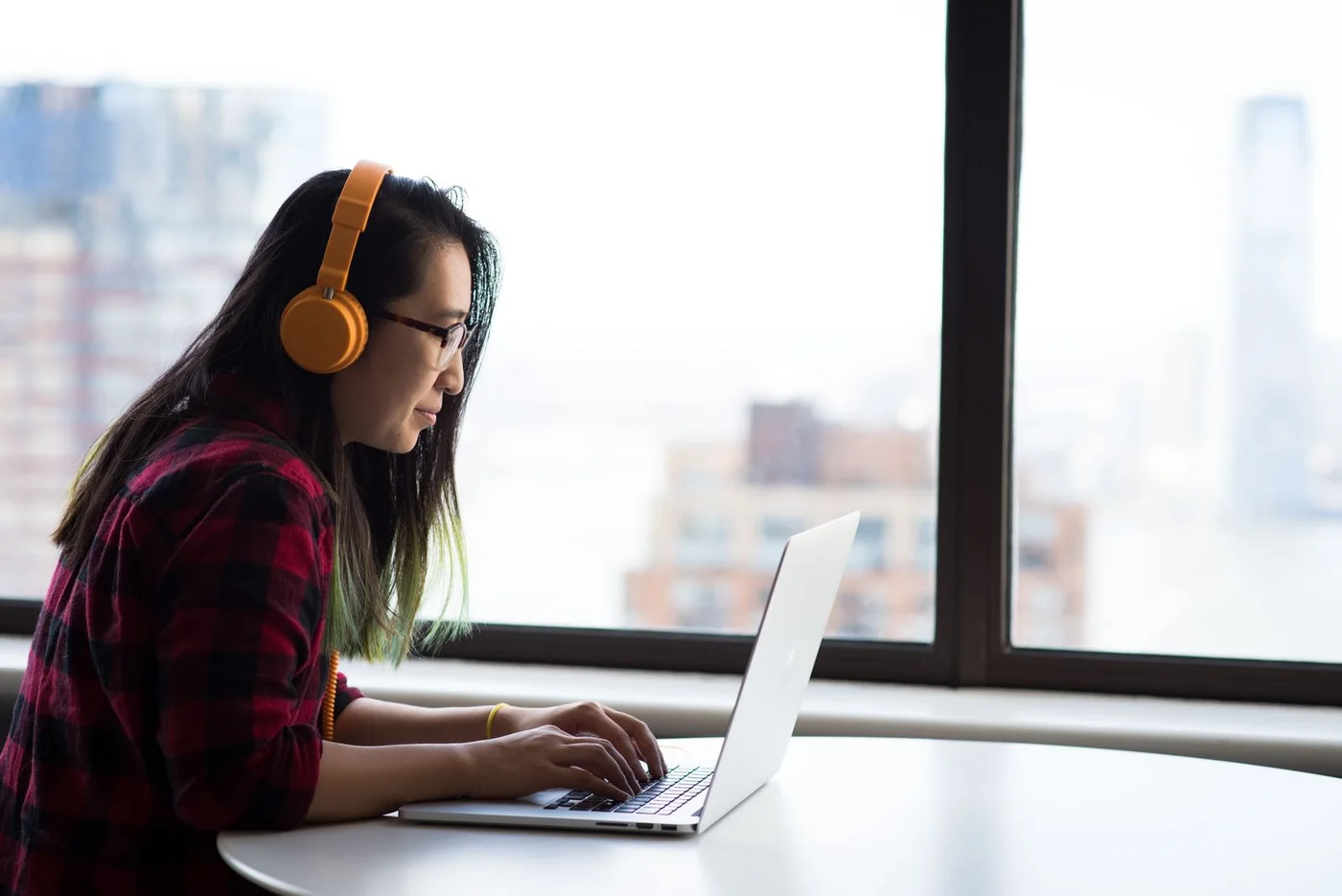 A woman wearing headphones while working on a laptop.
