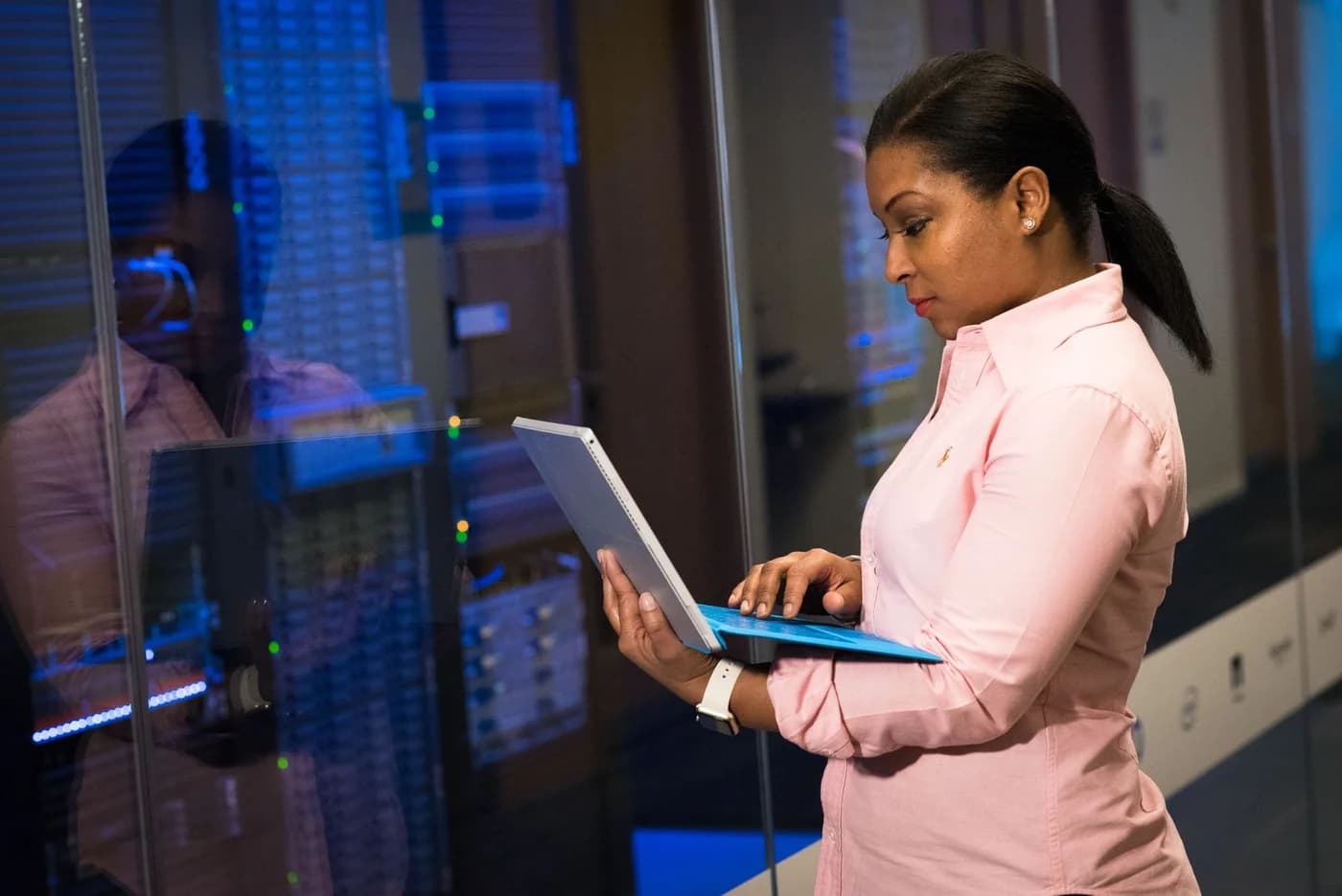 An engineer using a laptop in a server room.