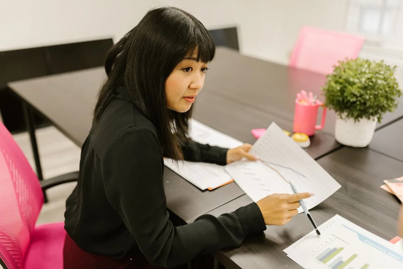 A woman reviewing printed charts at a desk.