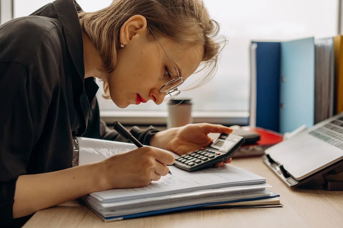 A woman checking accounts with a calculator and notebook.