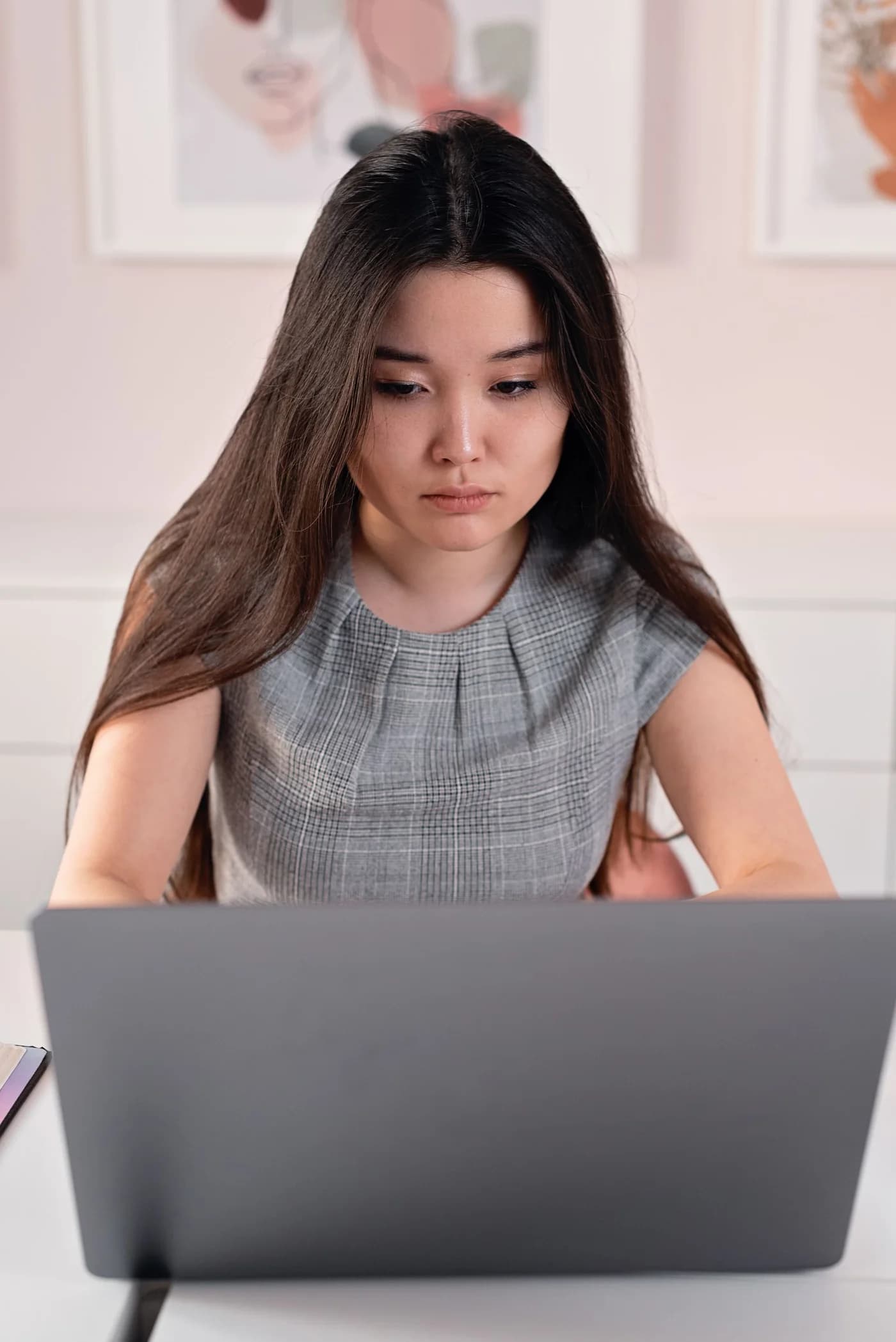 A woman working on a laptop in an office.